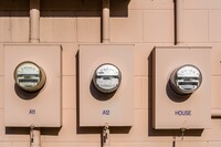 close-up of three electricity meters on the outside of a painted cinder block building