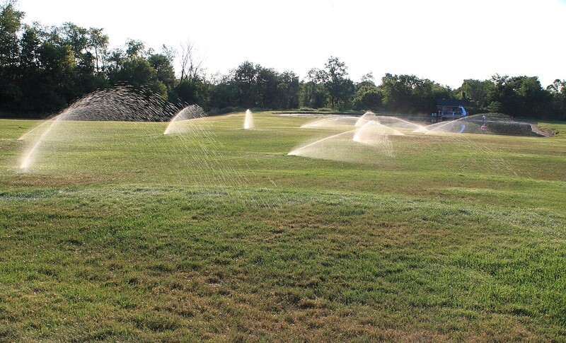 ten sprinklers spray water across a large lawn